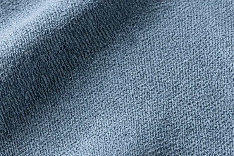 Close-up of steel-blue textured fabric with visible weave and folds filling the frame