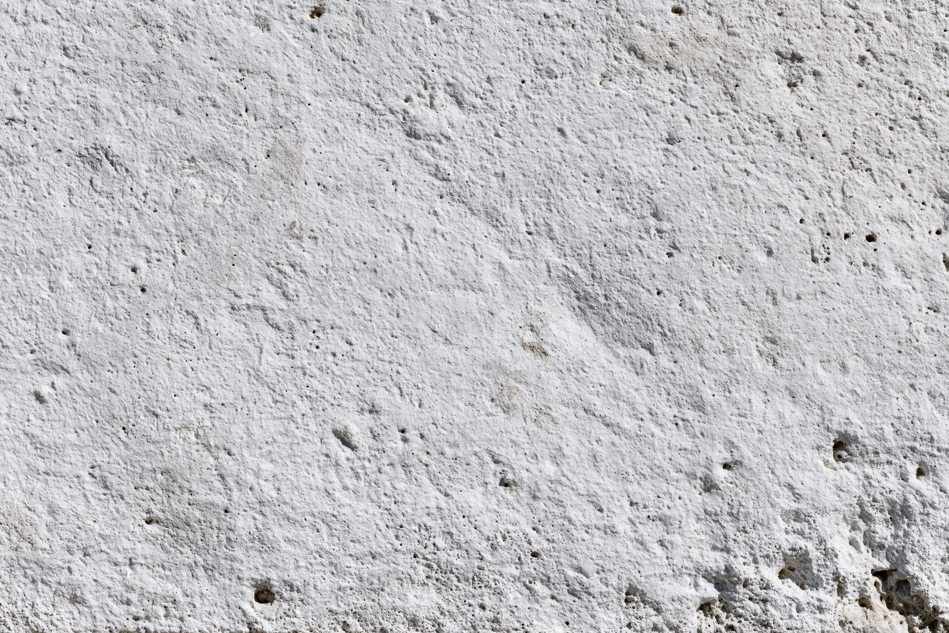 Close-up of a rough concrete wall surface with visible texture and small holes