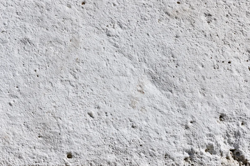 Close-up of a rough concrete wall surface with visible texture and small holes