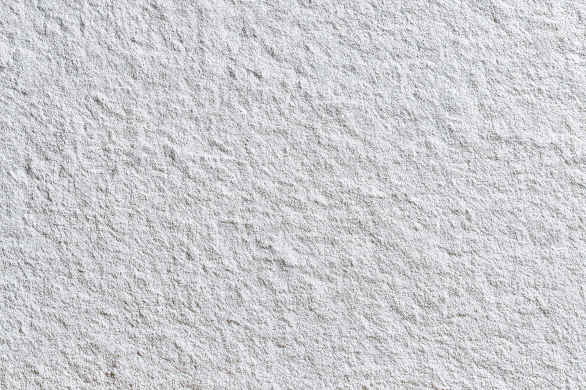 Close-up of a white stucco wall surface showing rough texture and paint finish