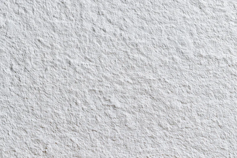 Close-up of a white stucco wall surface showing rough texture and paint finish
