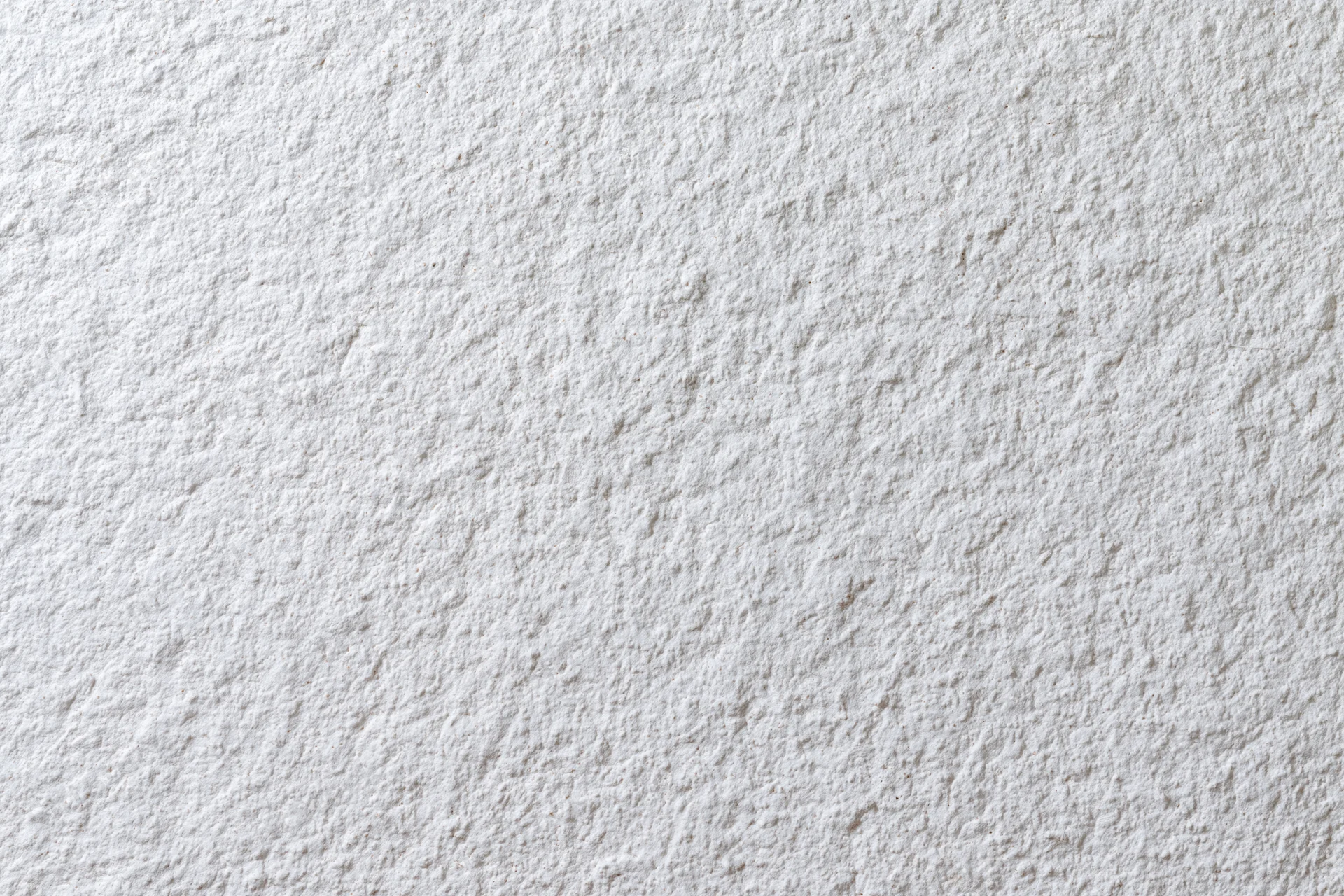 Close-up of a white stucco wall surface showing rough texture and paint finish