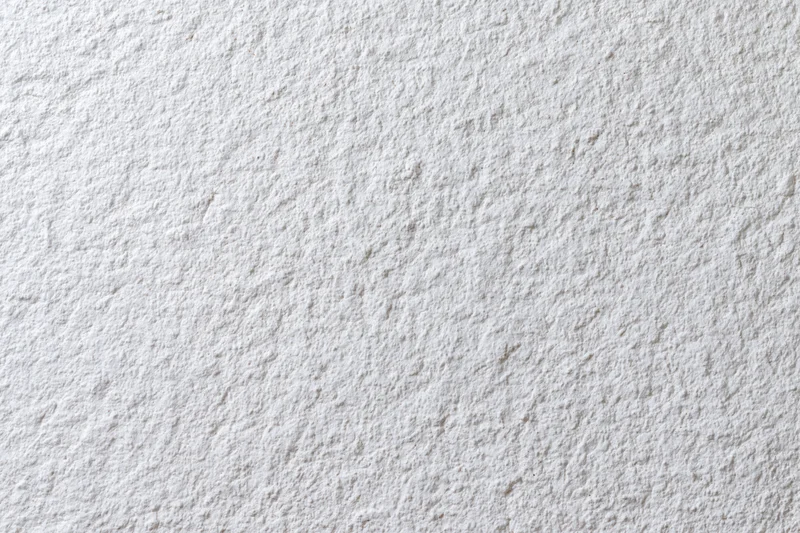 Close-up of a white stucco wall surface showing rough texture and paint finish