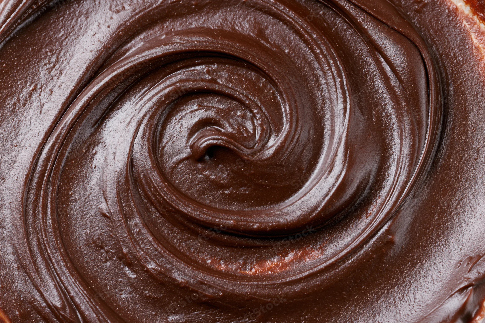 Close-up overhead view of dark chocolate ganache swirled on a dessert surface