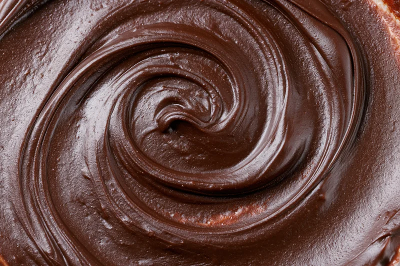 Close-up overhead view of dark chocolate ganache swirled on a dessert surface