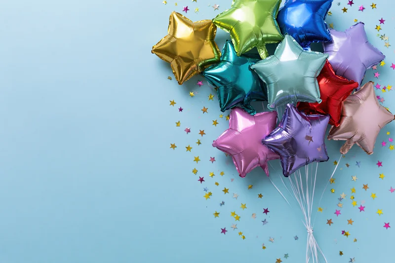 Cluster of metallic foil star-shaped balloons with scattered confetti on light blue background