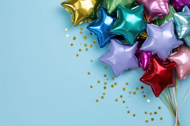 Cluster of metallic foil star-shaped balloons in assorted colors with gold star confetti on light blue background