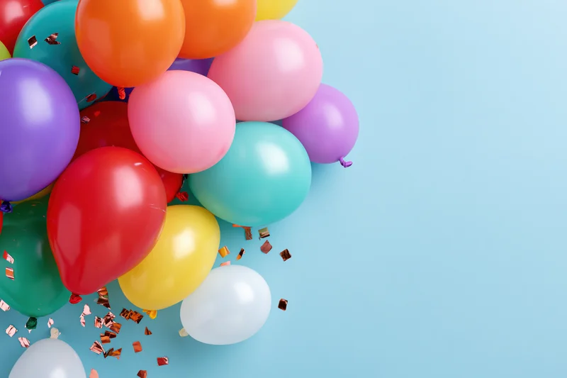 Cluster of multicolored latex balloons with confetti on light blue background