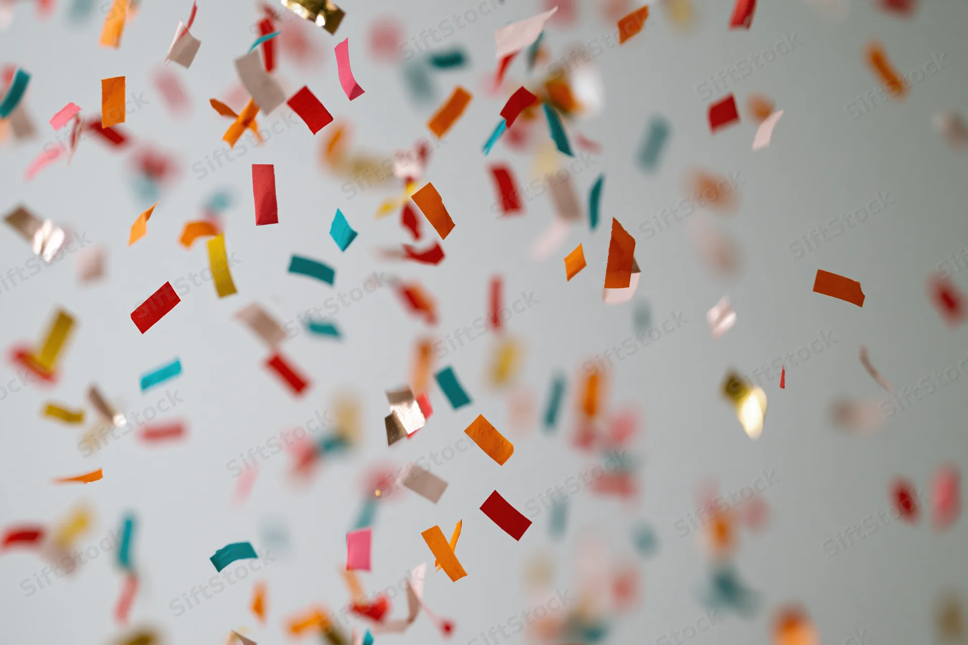 Colorful paper confetti pieces falling midair against a light background