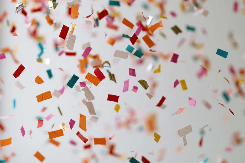 Colorful paper confetti pieces falling midair against a white background