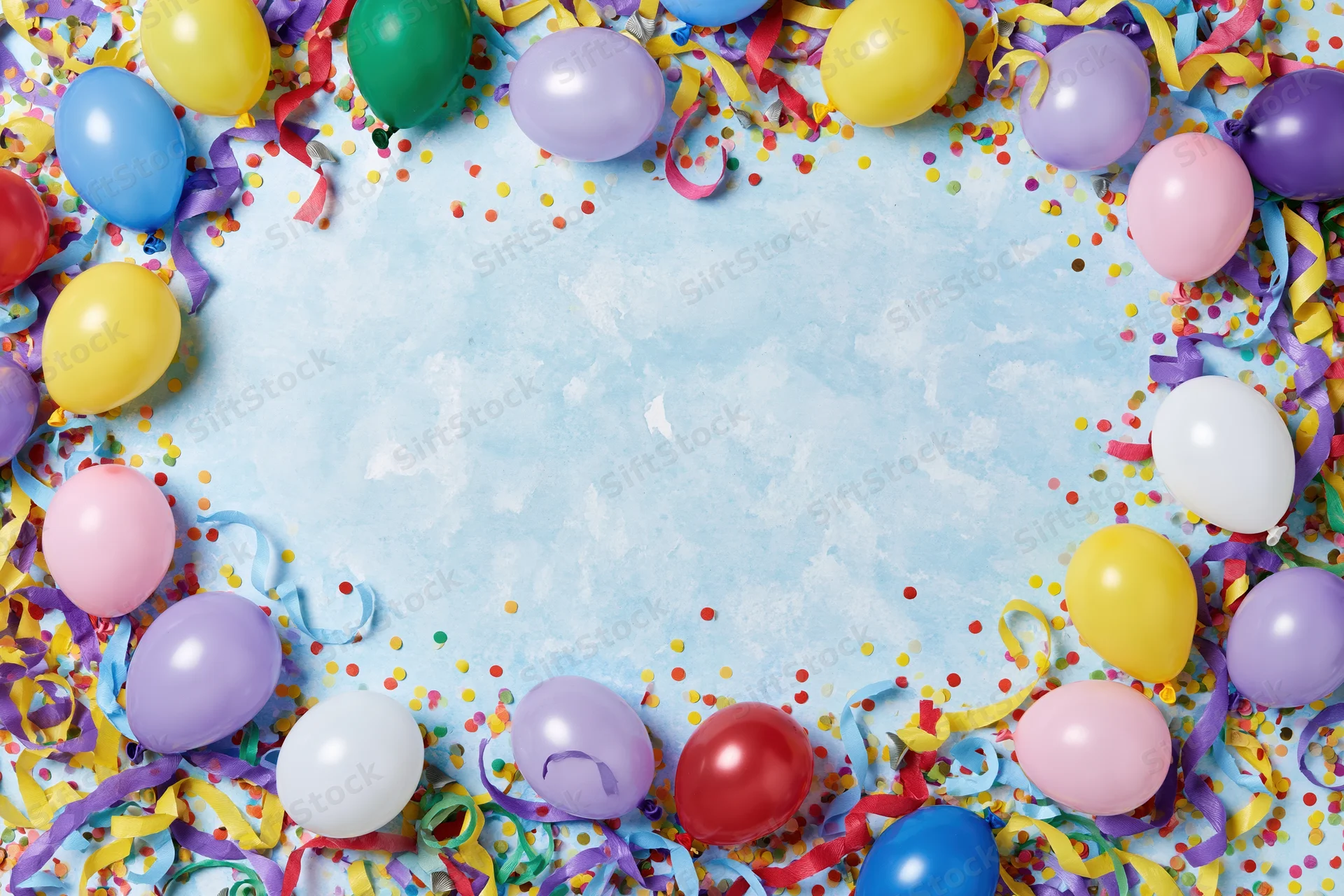 Colorful party balloons and streamers arranged in a circular frame around a light blue textured background with confetti
