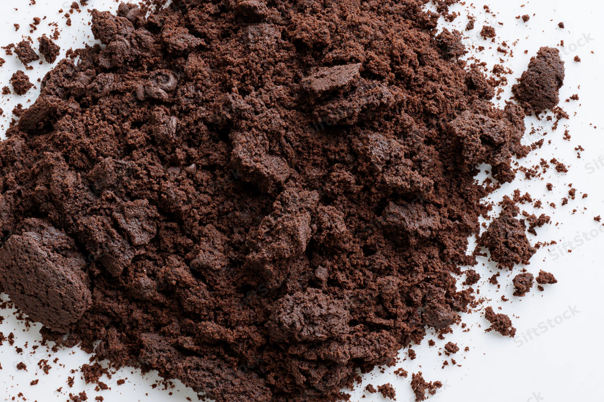 Chocolate cake crumbs scattered in a pile on a white surface