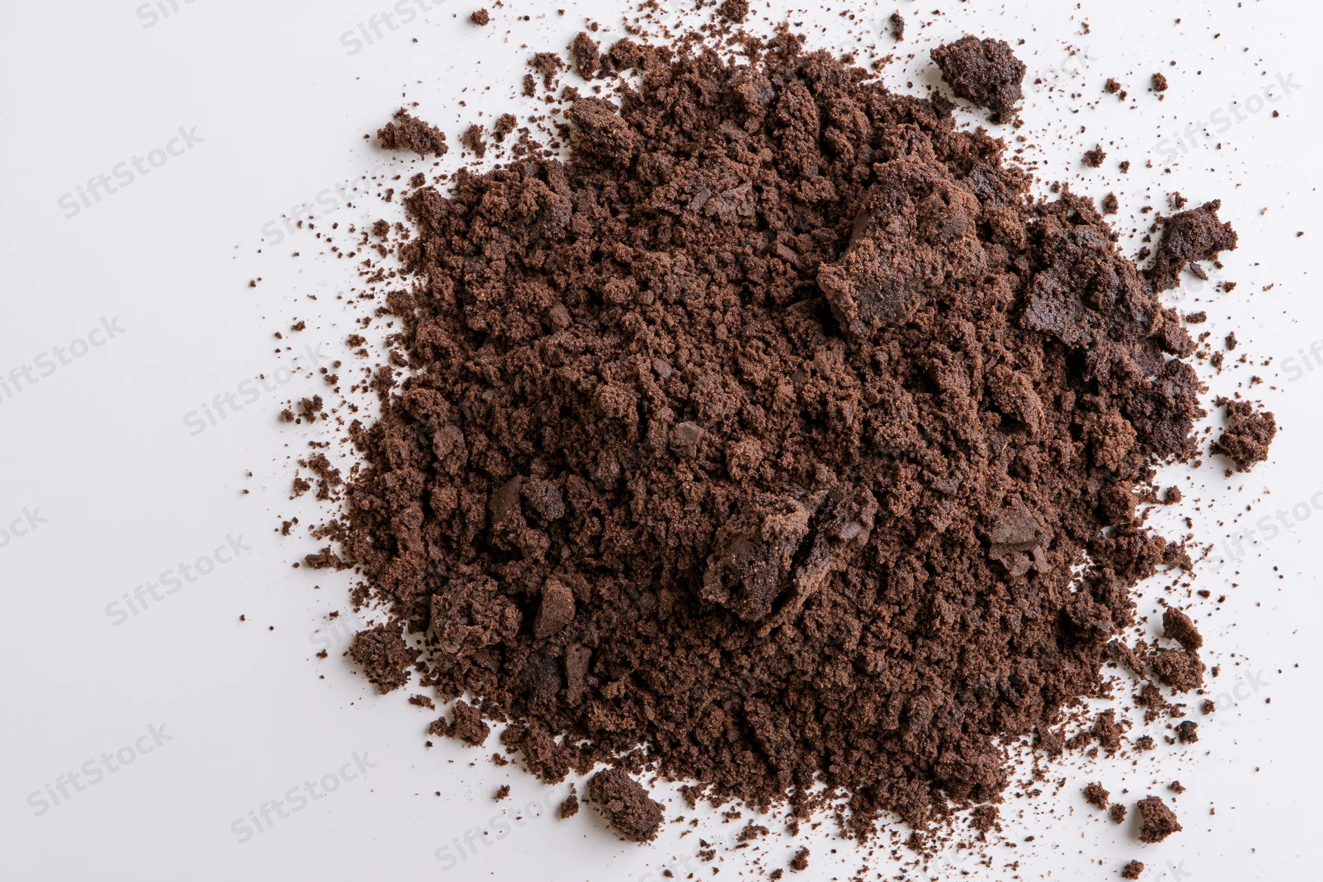 Pile of dark brown chocolate cake crumbs scattered on white surface