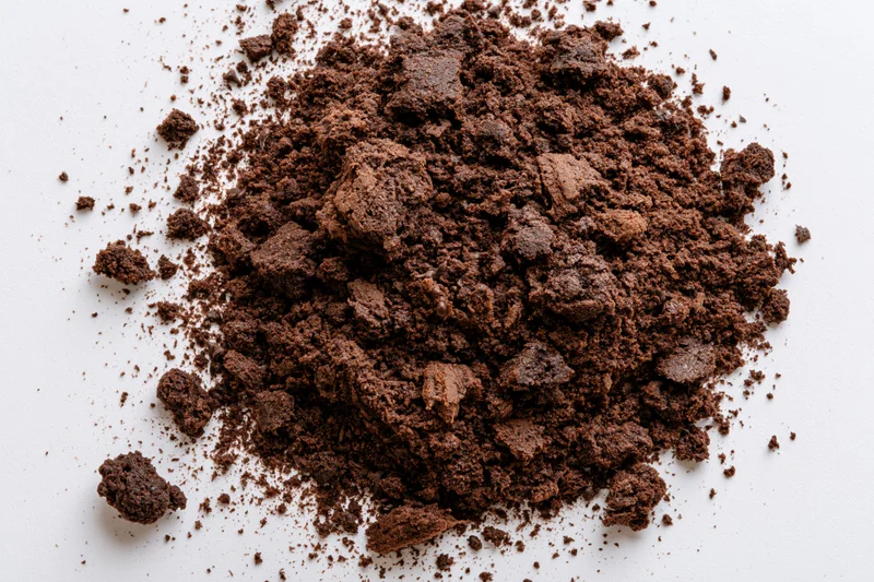 Pile of dark brown chocolate cake crumbs scattered on white surface