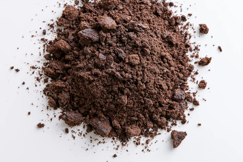 Pile of chocolate cake crumbs scattered on white surface