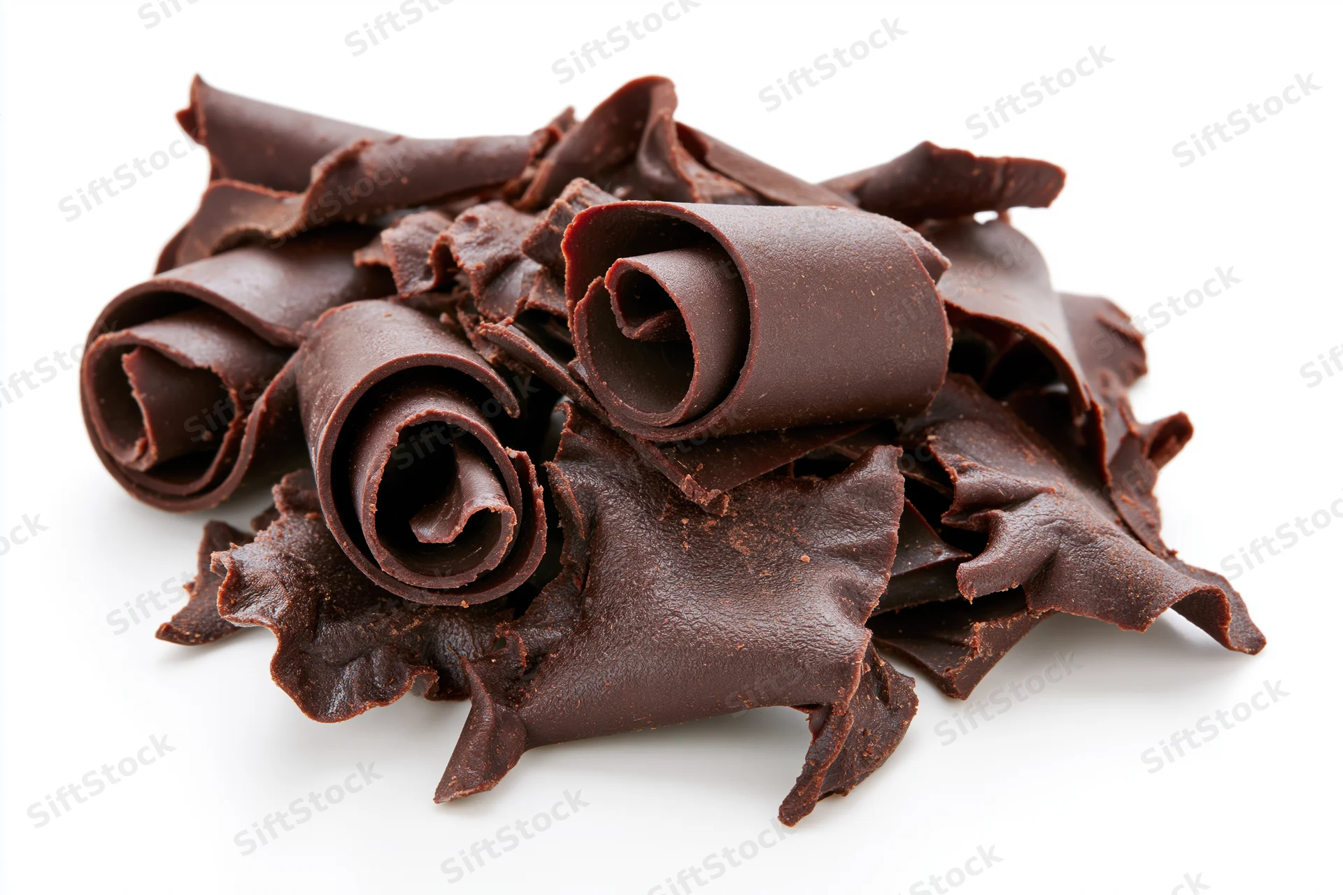 Dark chocolate curls and shavings piled together on white background