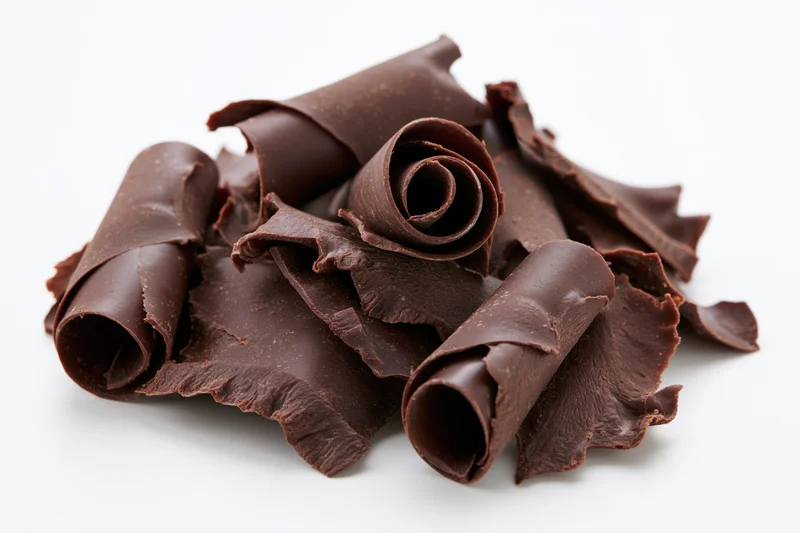 Dark chocolate curls and shavings piled together on white background
