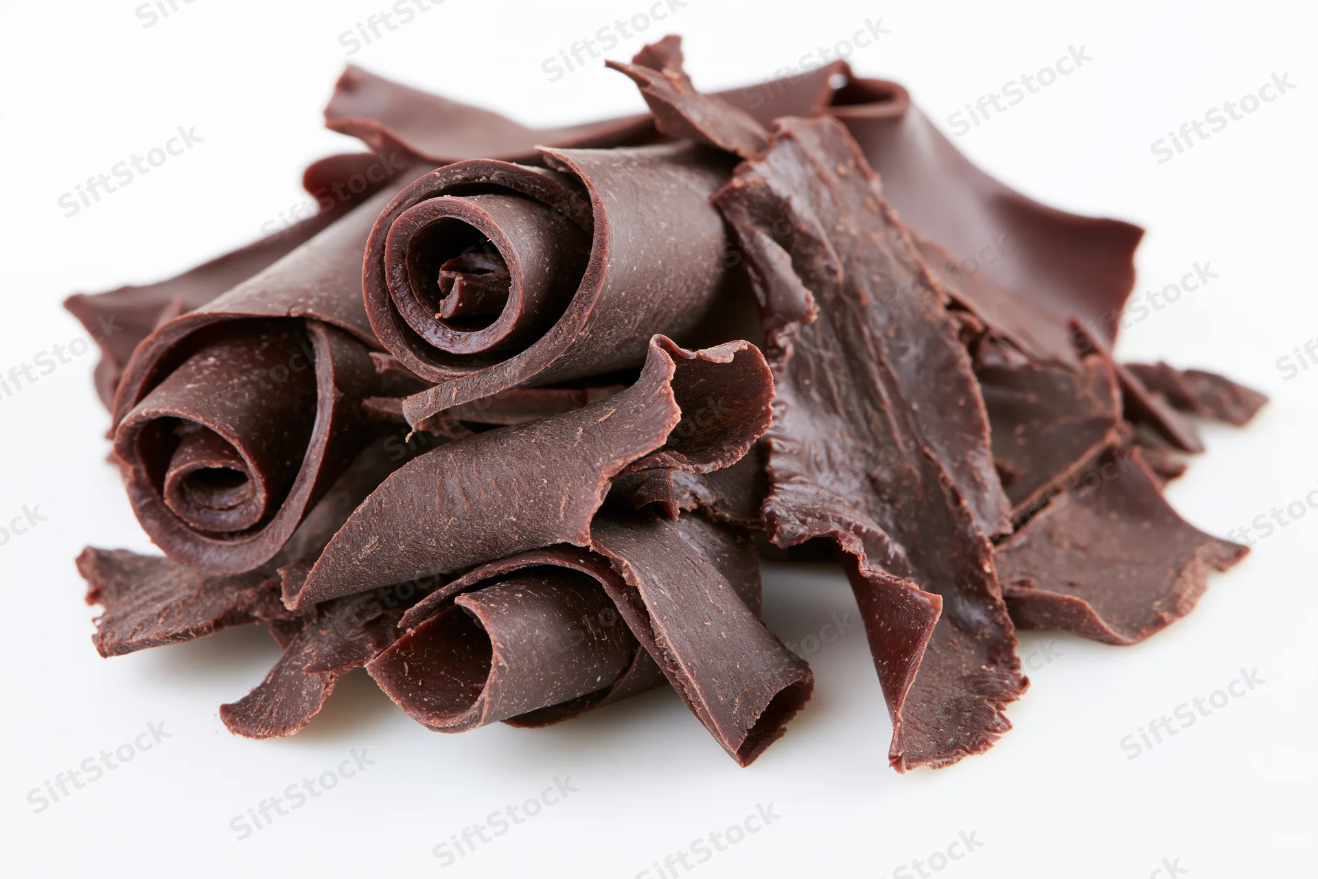 Dark chocolate curls and shavings piled together on white background