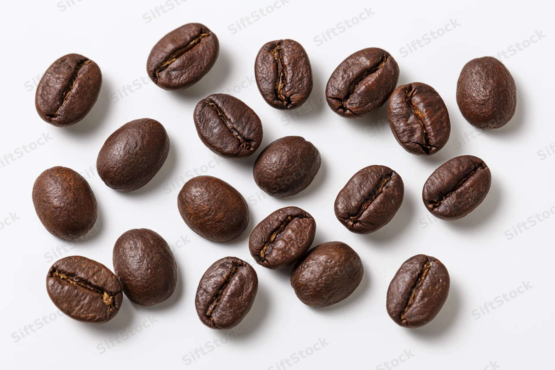 Roasted coffee beans scattered across a white background