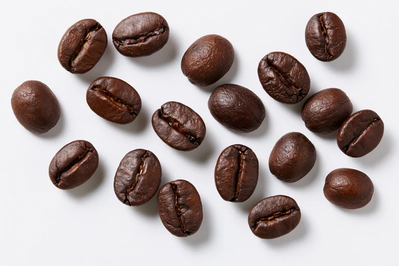 Roasted coffee beans scattered across a white background