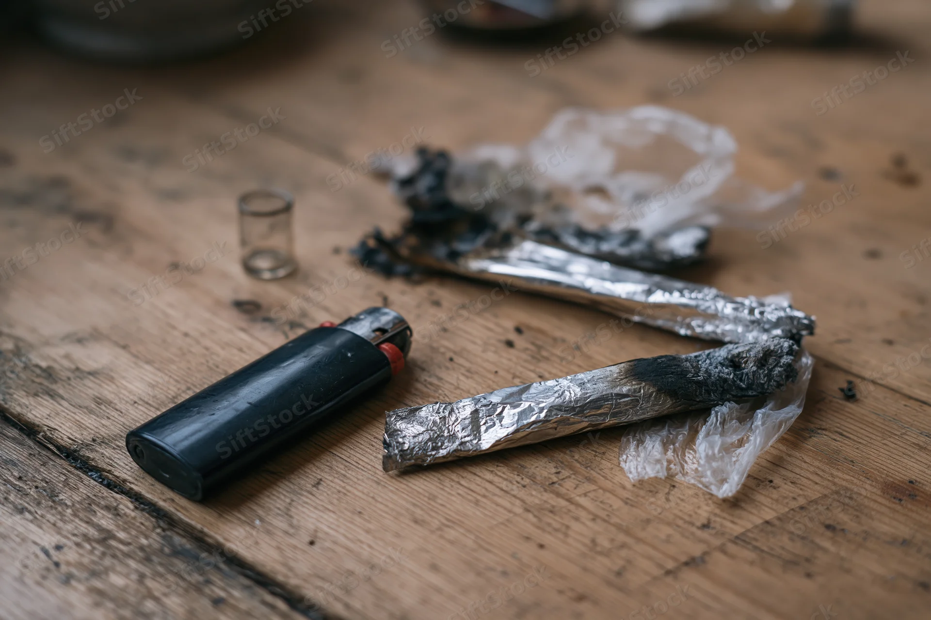 Burnt marijuana joints and a lighter on a worn wooden table