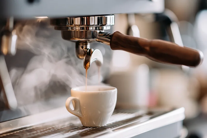 Espresso machine extracting coffee into a white ceramic cup on a drip tray