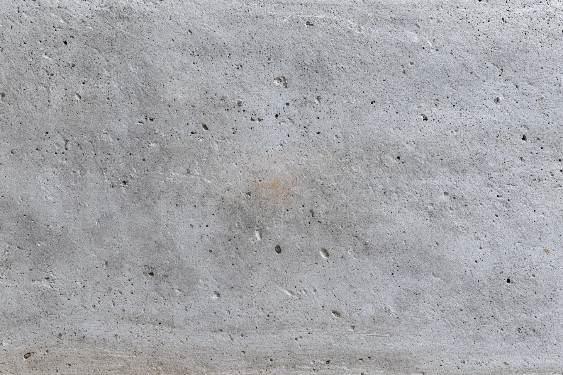 Flat gray concrete wall surface filling the frame with rough texture and small imperfections