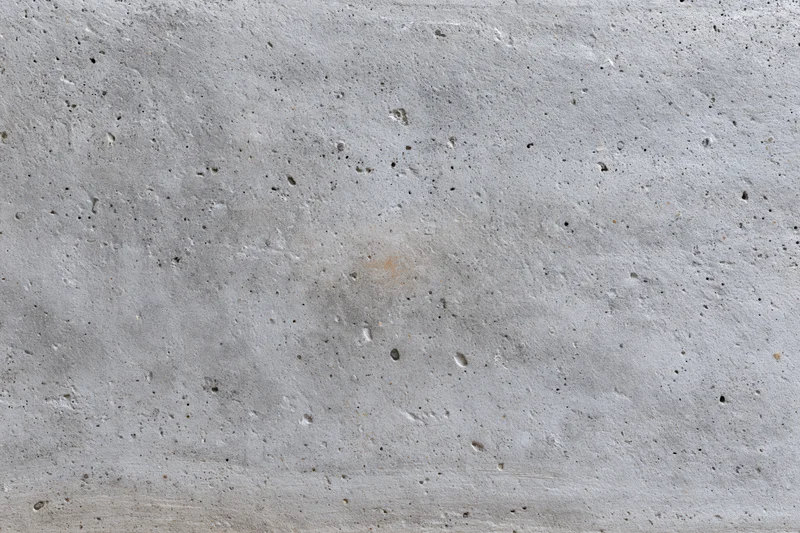 Flat gray concrete wall surface filling the frame with rough texture and small imperfections