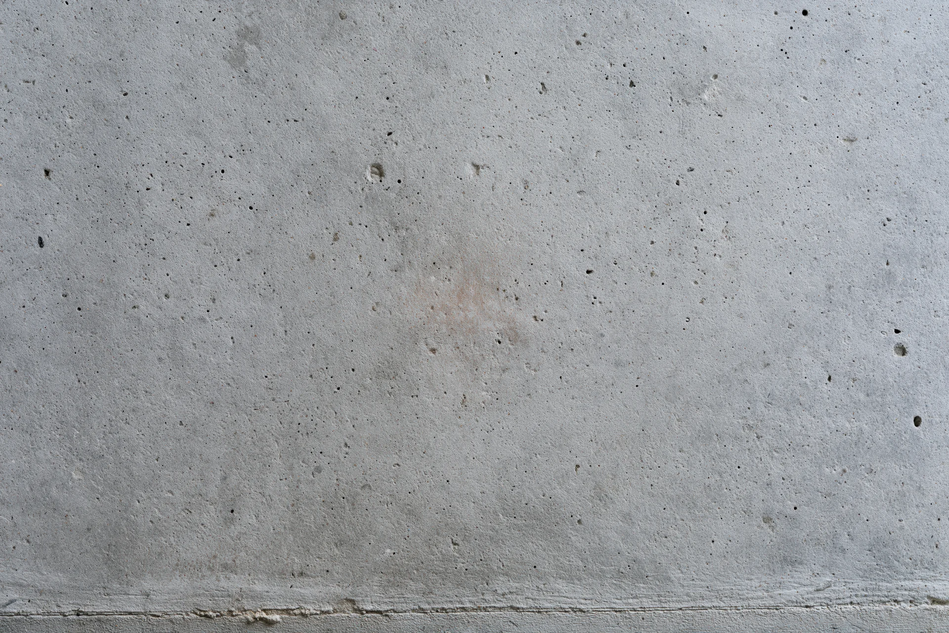 Flat concrete wall surface with visible texture and seam running horizontally across the frame