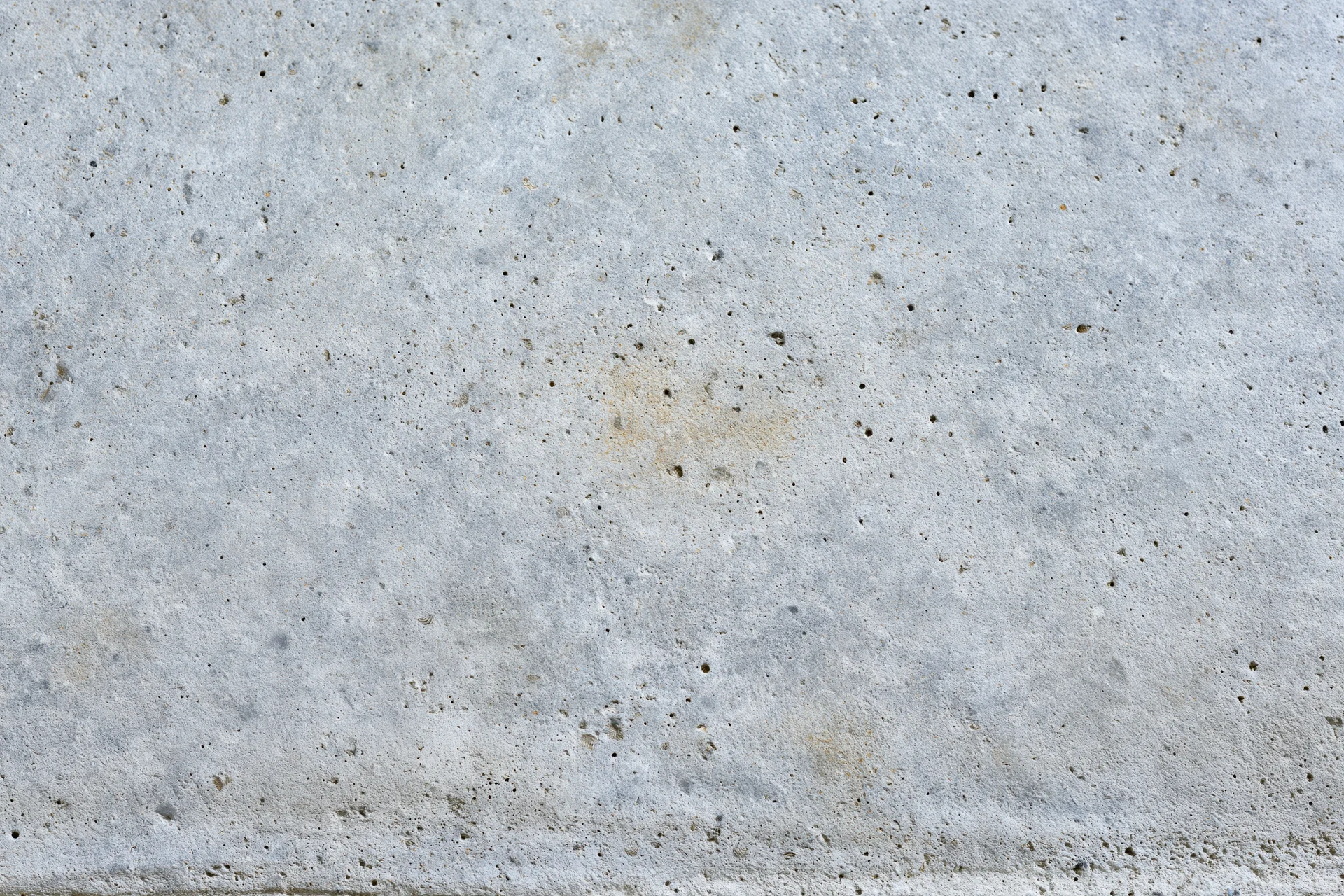 Close-up of a weathered concrete wall surface with small pits and discolorations