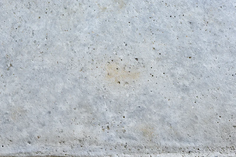 Close-up of a weathered concrete wall surface with small pits and discolorations