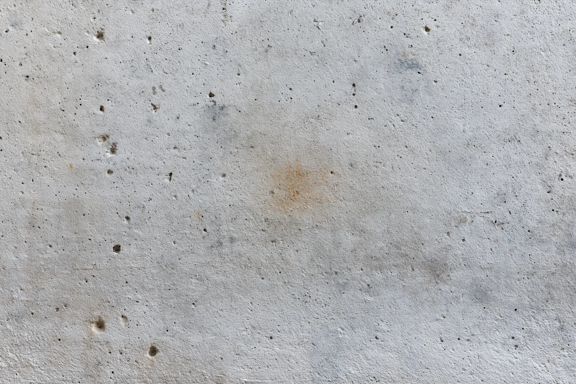 Close-up of a weathered concrete wall surface with stains and pores