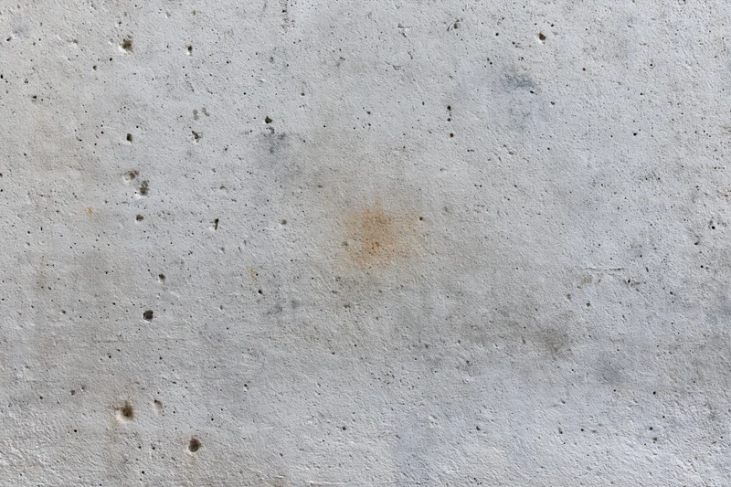 Close-up of a weathered concrete wall surface with stains and pores