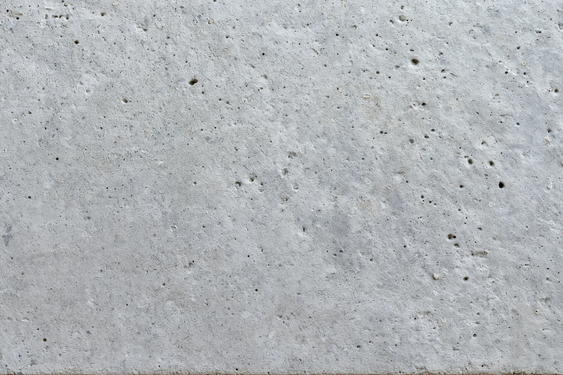 Flat gray concrete surface filling the frame with rough texture and small pits
