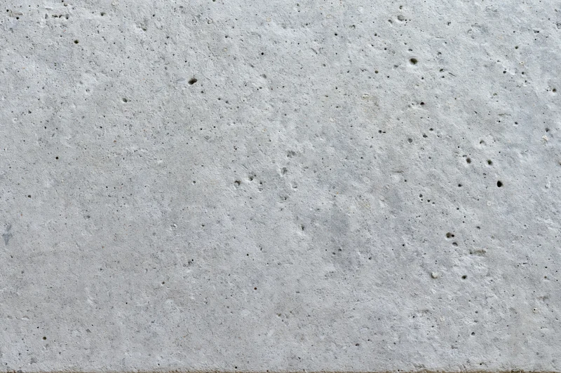 Flat gray concrete surface filling the frame with rough texture and small pits