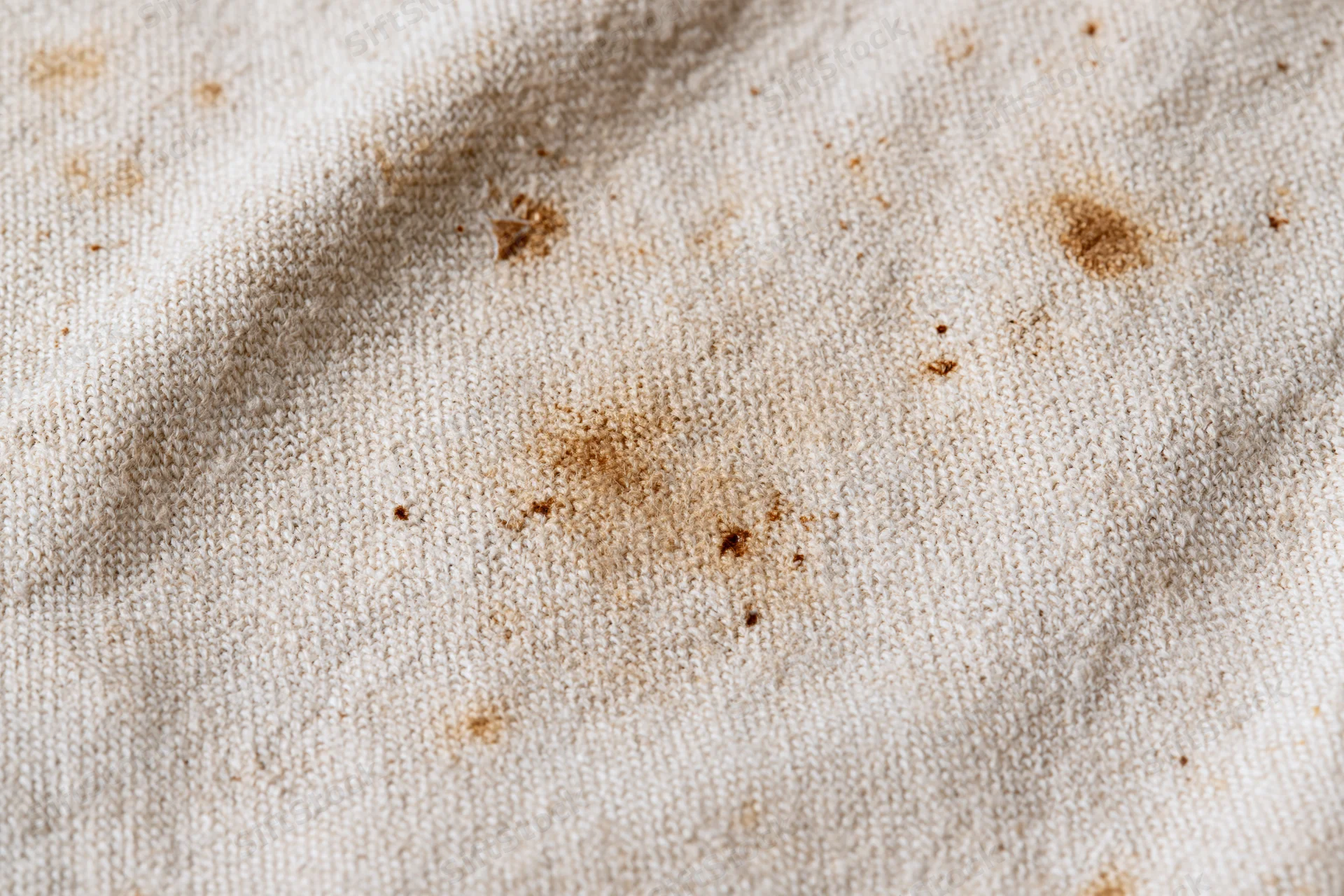 Close-up of aged natural linen canvas fabric with brown stains and texture filling the frame