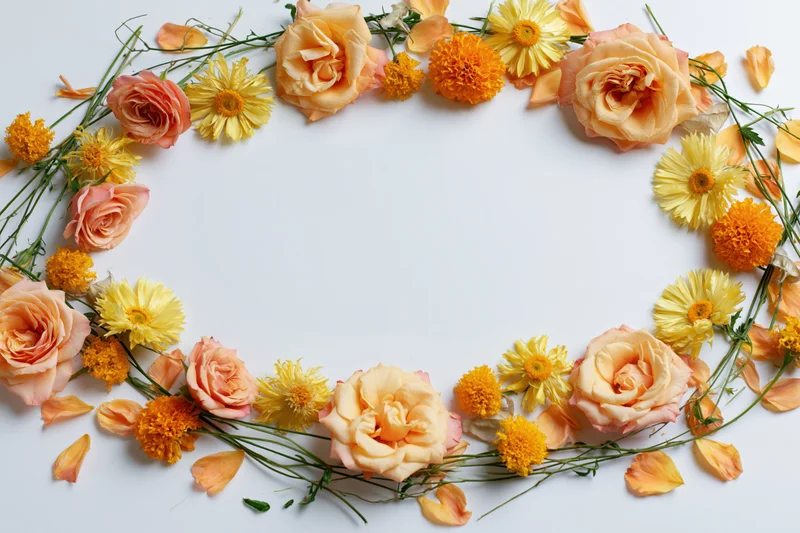 Circular floral arrangement of peach roses, yellow daisies and orange marigolds on white background with copyspace