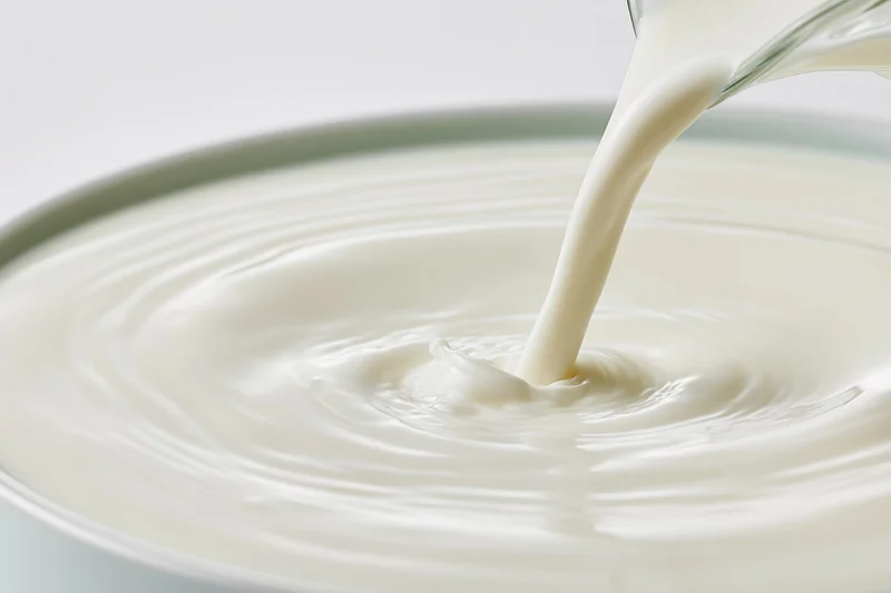 Milk pouring from a glass into a bowl creating ripples
