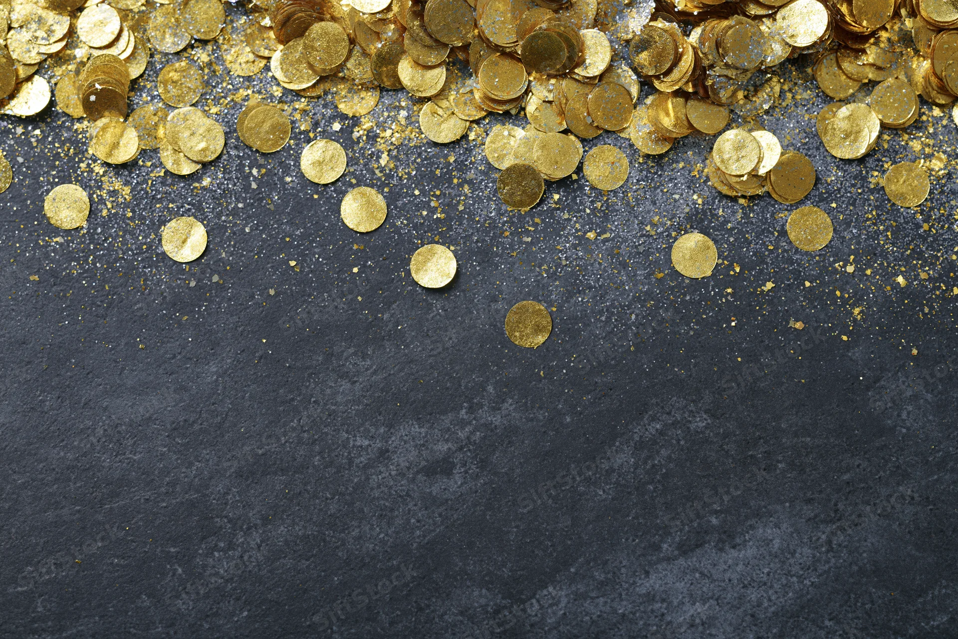Gold metallic confetti and glitter scattered across dark textured surface with copyspace below