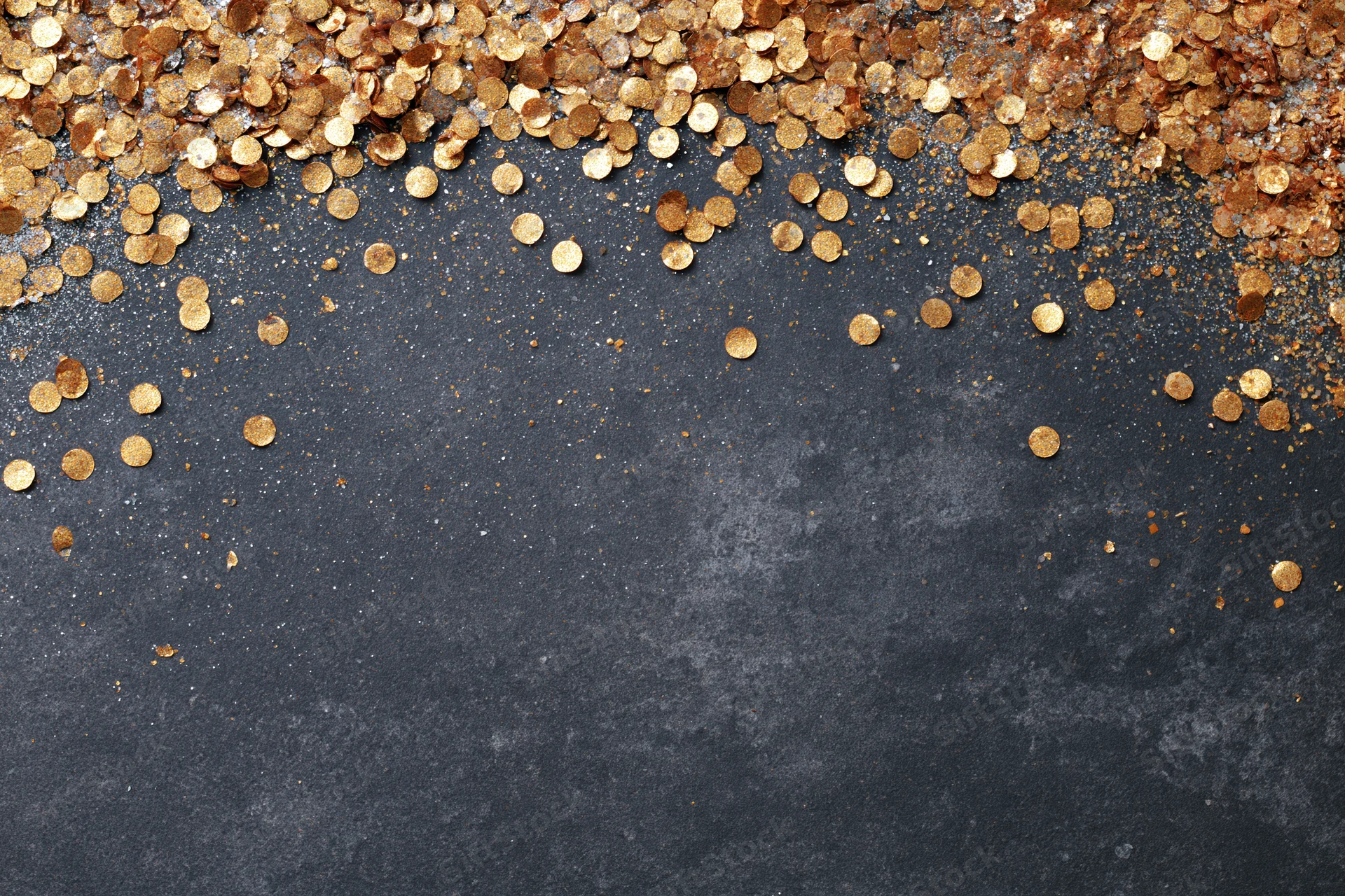 Gold metallic confetti and glitter scattered across dark textured surface with copyspace below