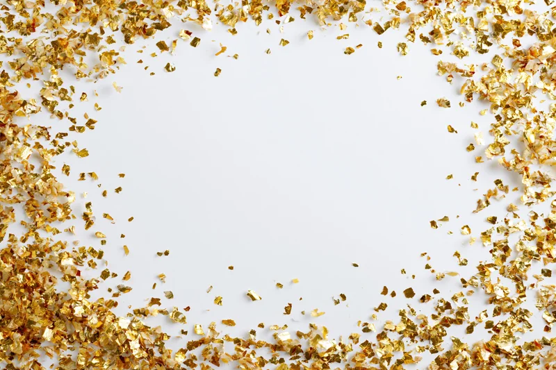 Gold metallic confetti scattered in a frame around a white background with copyspace