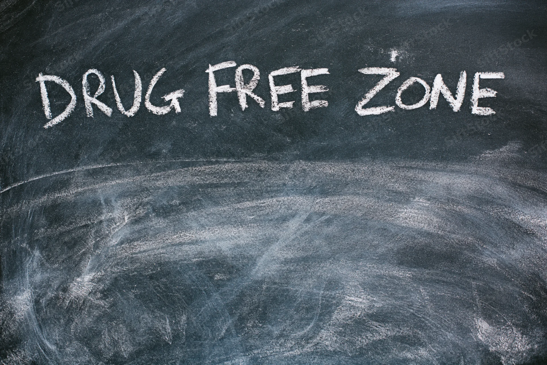 Handwritten chalk text reading drug free zone on a blackboard in a classroom