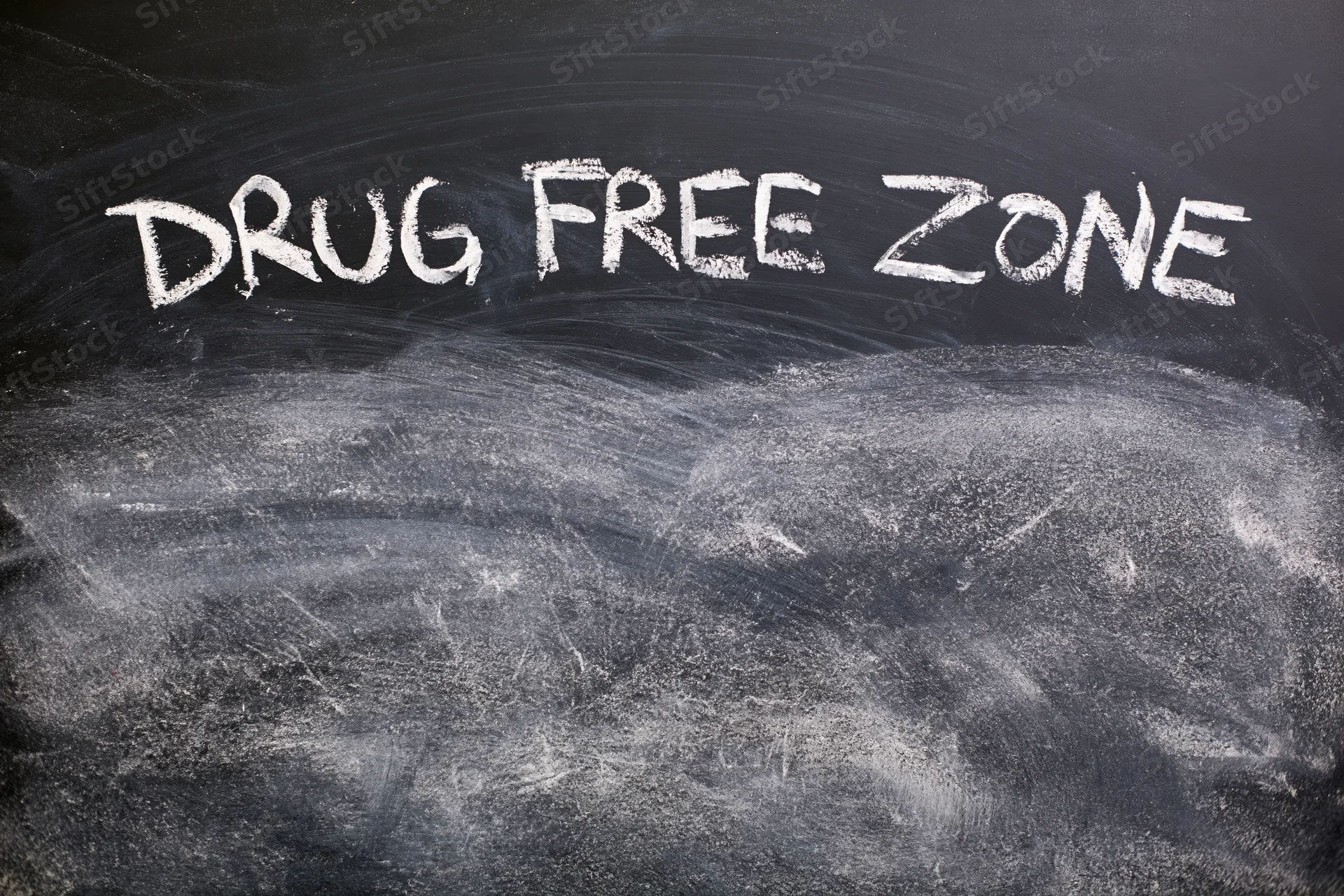 Handwritten chalk text reading drug free zone on a blackboard surface