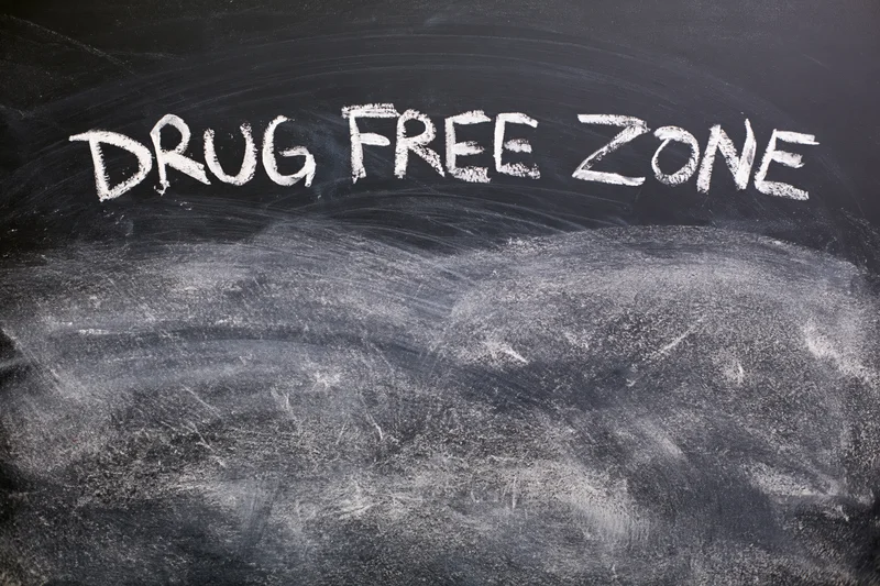 Handwritten chalk text reading drug free zone on a blackboard surface