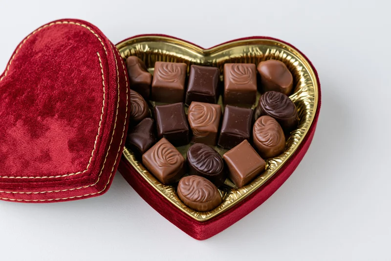 Heart-shaped chocolate gift box open on white background