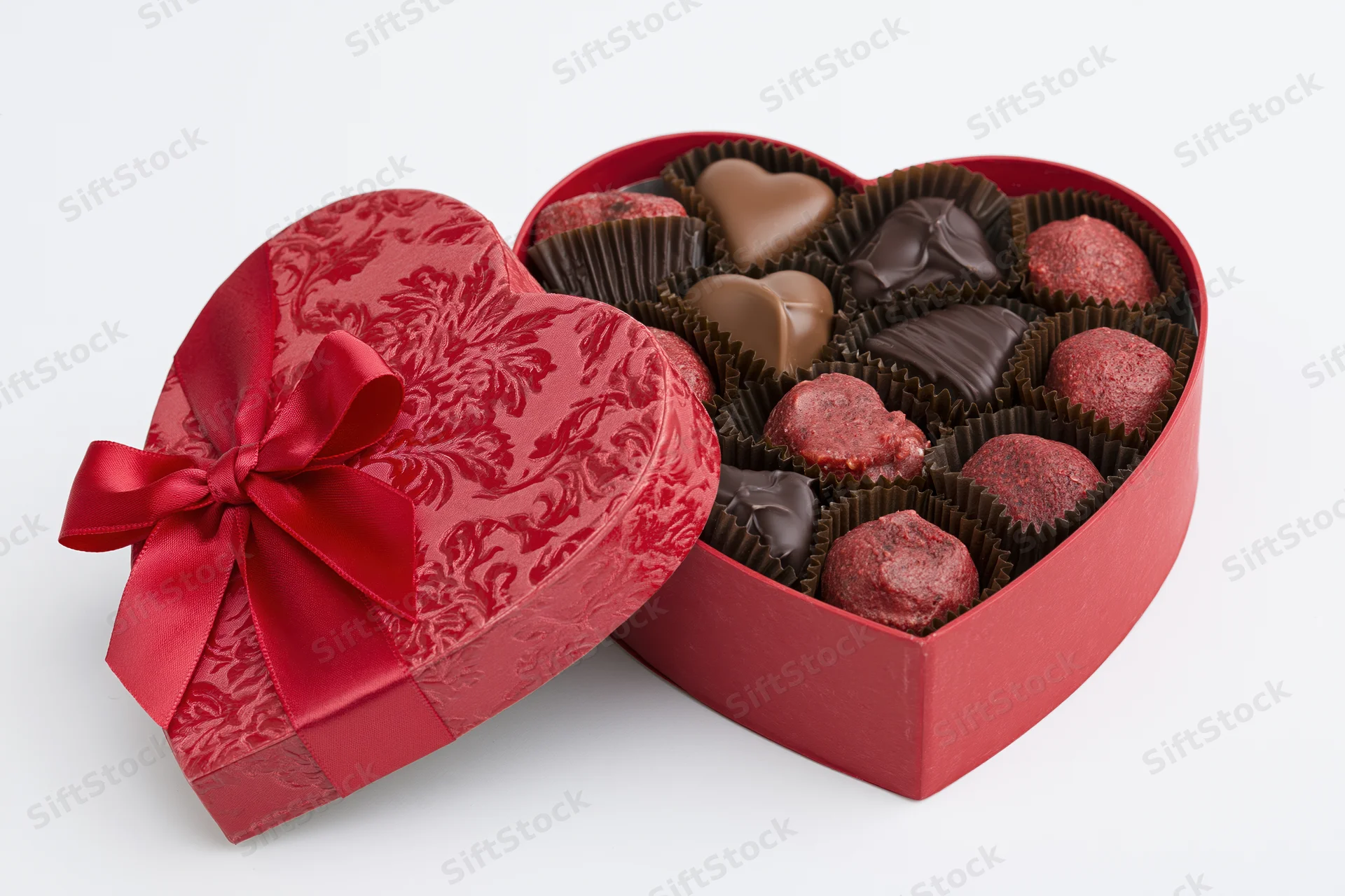 Heart-shaped red gift box filled with assorted milk and dark chocolates on white background