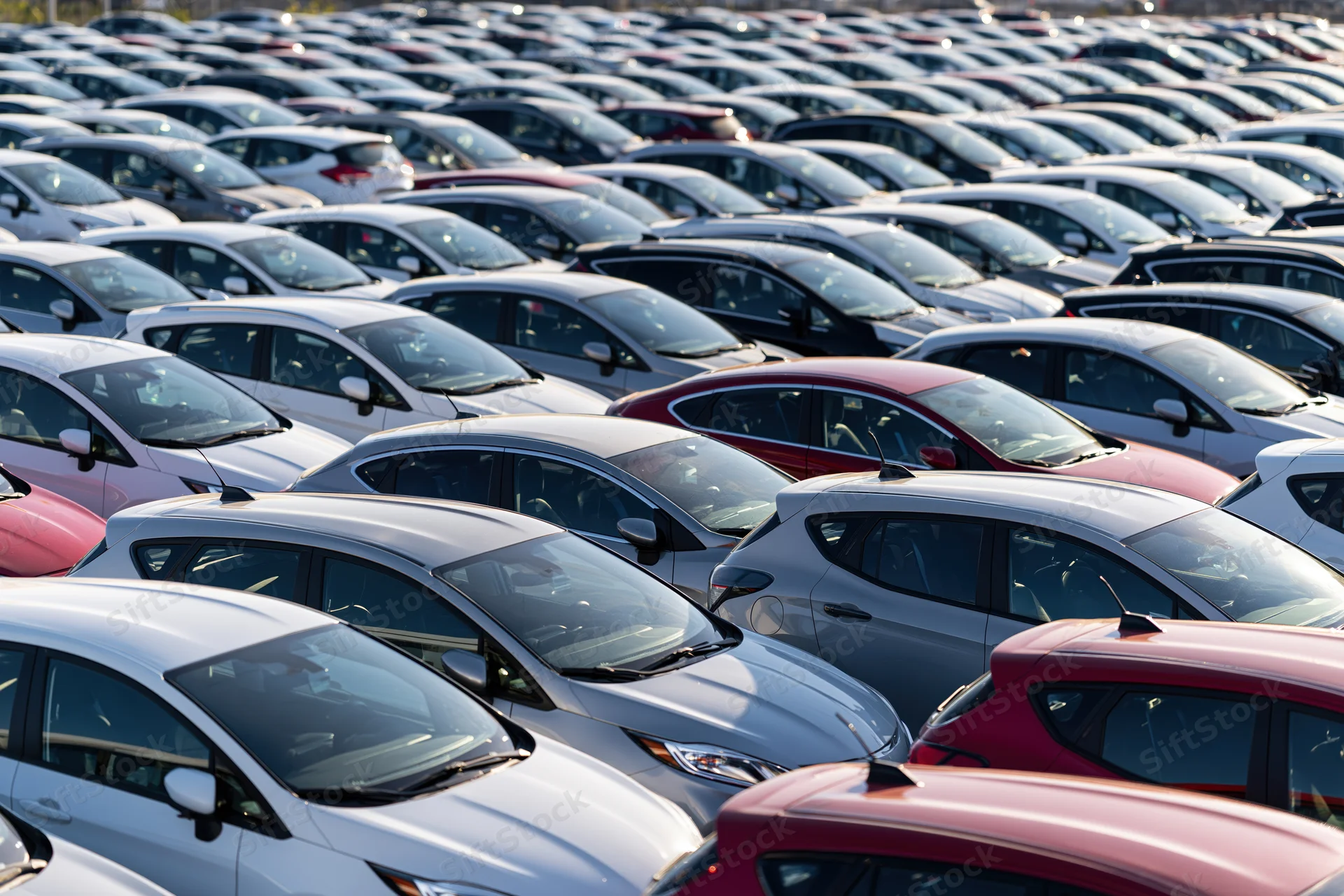 Rows of new cars parked tightly in an outdoor dealership lot