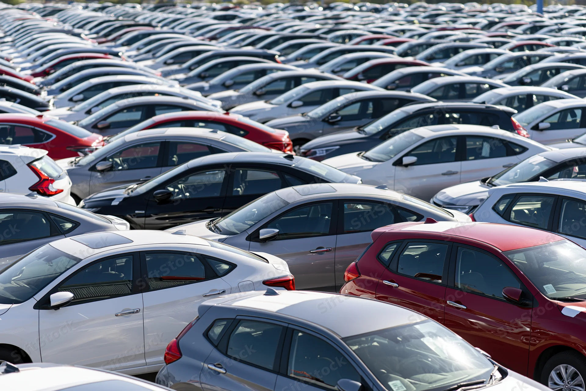 Rows of new cars parked tightly in an outdoor dealership lot