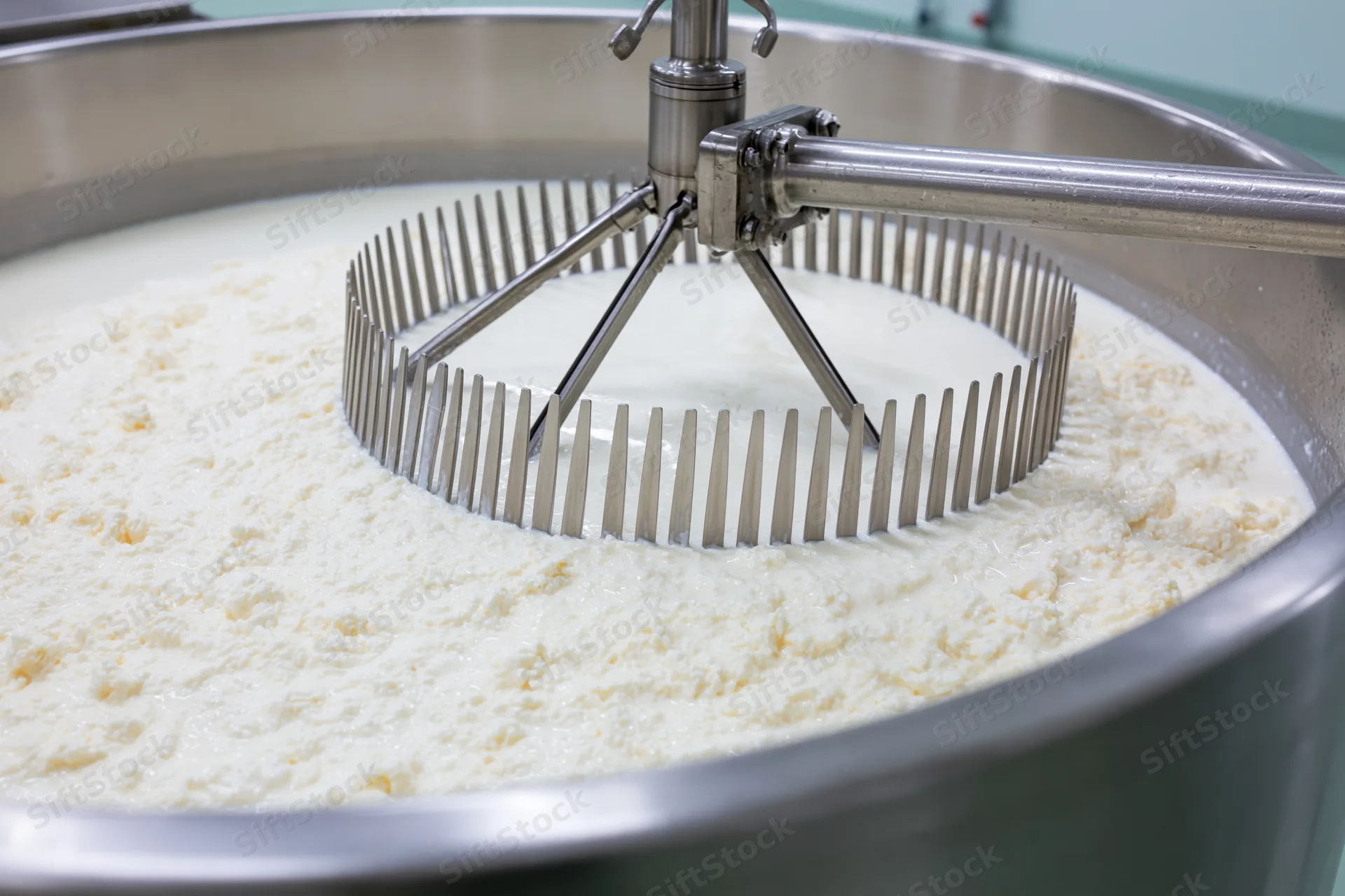 Stainless steel cheese vat with rotating agitator mixing curd and milk during cheese production