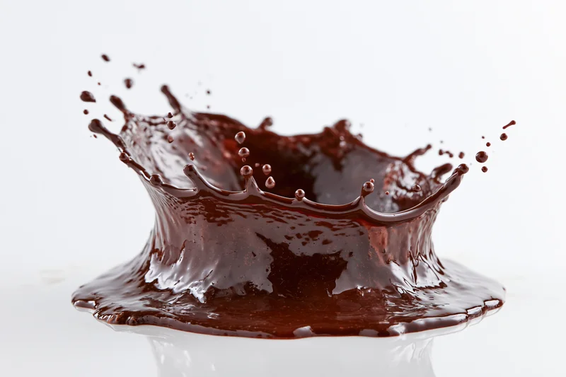 Liquid chocolate splashing into a crown shape against a white background